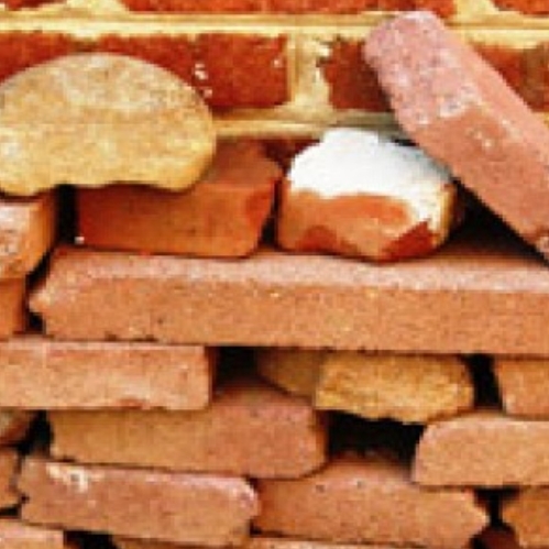 Photo of bricks piled in front of a brick wall