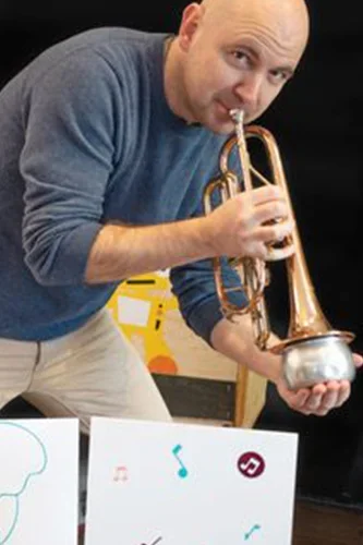 Photo of a trumpet player behind children's drawings